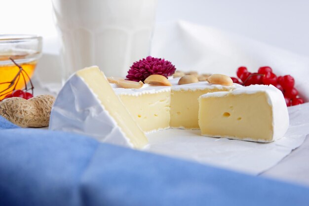 Camembert nuts berries honey a glass of milk and a cookie with seeds on a light background Breakfast food Closeup