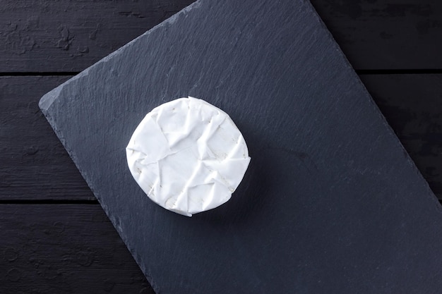 Camembert op leisteenplaat Zachte kaas met schimmel op donkere achtergrond Kaas op houten planken