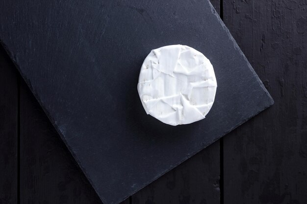 Camembert op leisteenplaat Zachte kaas met schimmel op donkere achtergrond Kaas op houten planken