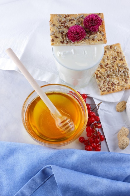 Camembertnoten, bessen, honing, een glas melk en een koekje met zaden op een lichte achtergrond Ontbijtvoedsel Close-up