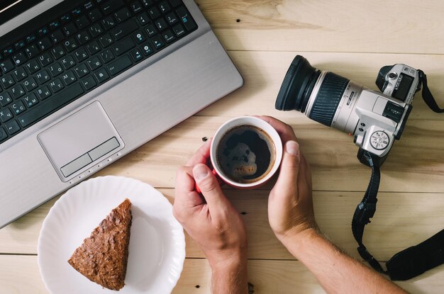 写真 木製の背景にカメラとラップトップ コーヒーとケーキ