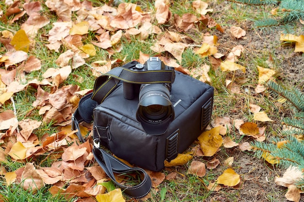 Fotocamera su una borsa tra foglie gialle