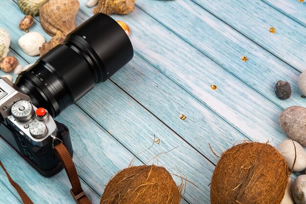 Foto fotocamera, noci di cocco e conchiglie su uno sfondo di legno blu. tema marino