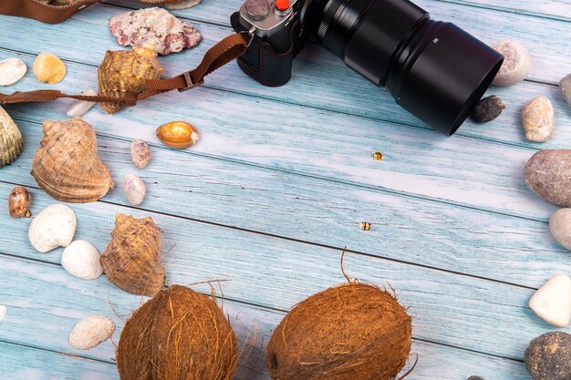 Camera,coconuts and shells on a blue wooden background.Marine theme