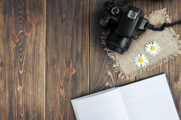 Fotocamera, tastiera del computer e fiori di campo su legno scuro.