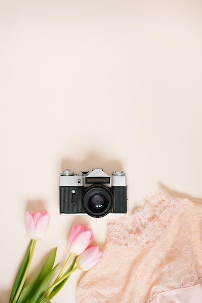 Camera dameskleding en een boeket tulp bloemen op een beige achtergrond met kopieerruimte Flat lag reisblogger