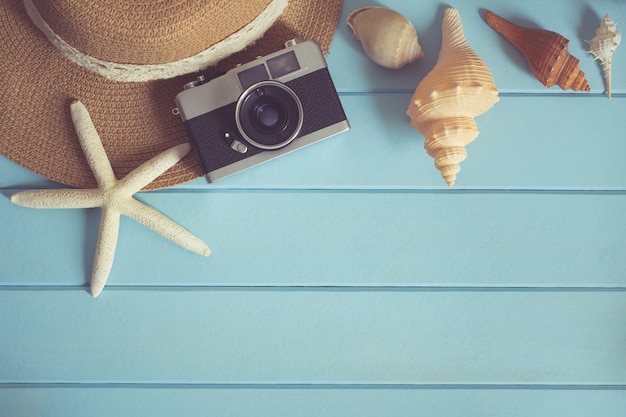 Foto camera en shells op de houten vloer van het blauw, de zomerconcept, retro filter