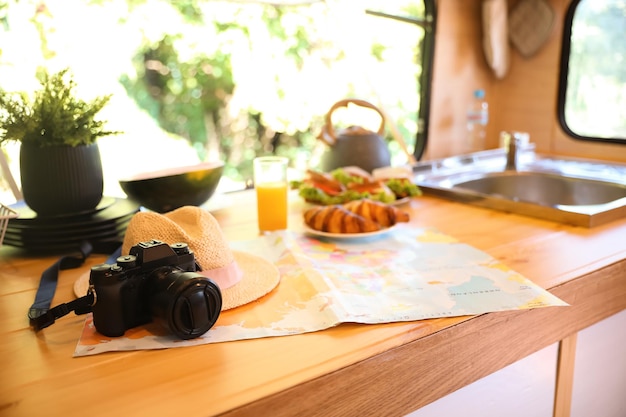 Camera hat and world map on wooden table in modern trailer Camping vacation