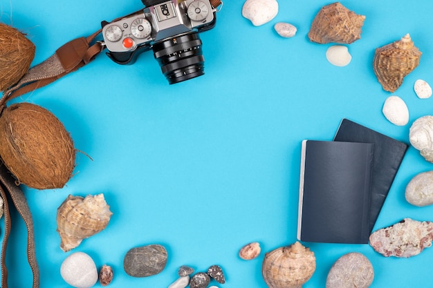 Camera, kokosnoten, schelpen en documenten op een blauwe achtergrond. Achtergrond voor de reiziger.