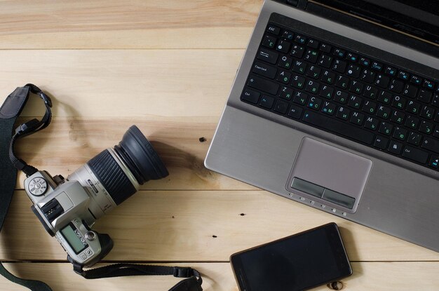 Camera and laptop on wooden background