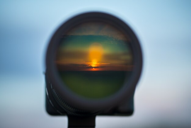 The camera lens with a landscape reflection on the background of the sky