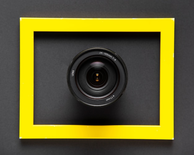 Объективы фотоаппарата внутри желтой рамки на черном фоне