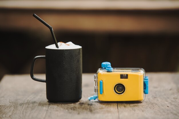 Camera met koffie in café op houten tafel