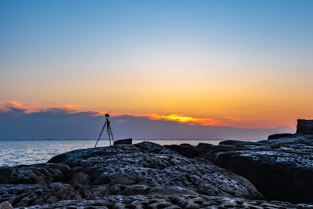 Фото Камера на штативе снимает красочный восход солнца на море