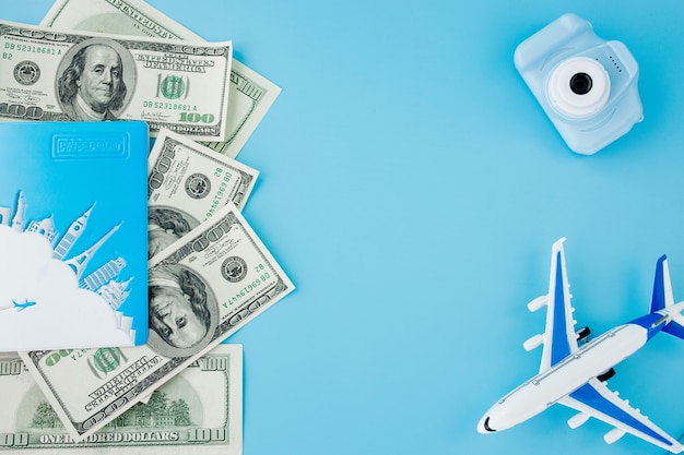 Camera, passport, dollars and airplane on light blue