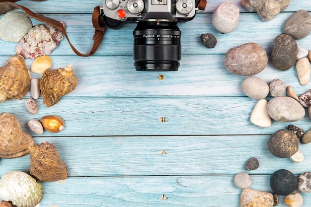 Camera and seashells on a blue wooden background.Marine theme