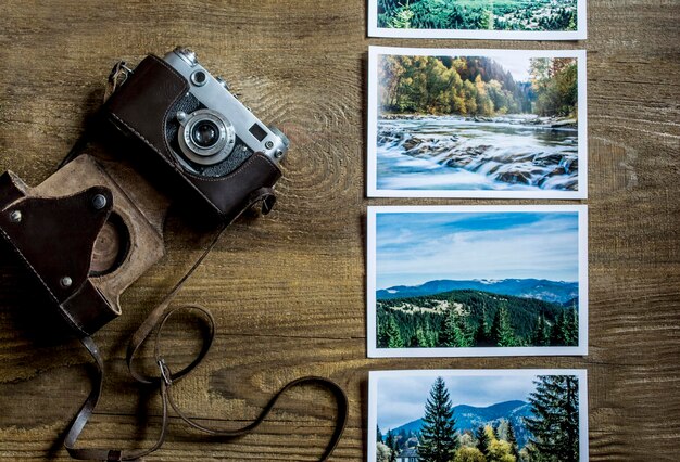 A camera on wooden boards. The old camera lies on a wooden background near pictures with a landscape. View from above