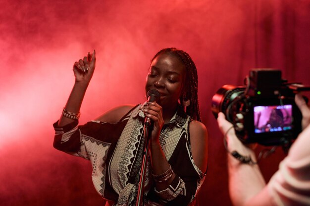 Foto cameraman che filma una donna nera in un video musicale