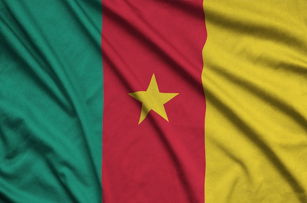 Cameroon flag is depicted on a sports cloth fabric with many folds.