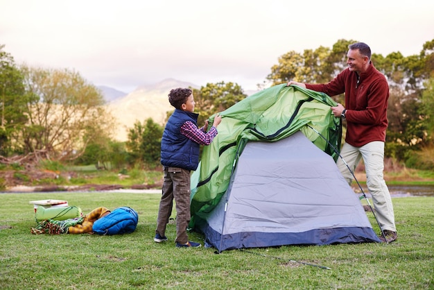 Camp is almost ready Shot of a father and son setting up a tent together while camping