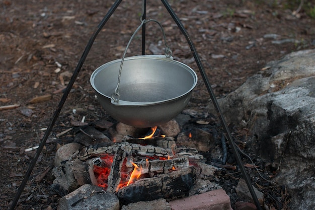 A camp pot hangs over the fire on a tripod Cooking on a camping trip hiking