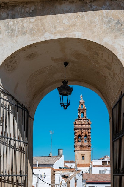 Campanario barroco de la iglesia san Miguel Arcangel visto a traves del arco de entrada a la alcazaba de la villa Jerez de los Caballeros Spanje