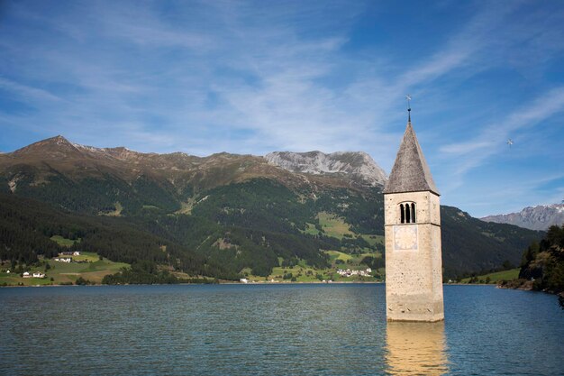 Foto campanile di curon venosta vecchia of ondergedompelde toren van reschensee-kerk diep in het resias-meer in de ochtend in de vallei van trentinoalto in zuid-tyr of alto adige in bolzano of bozen stad in italië