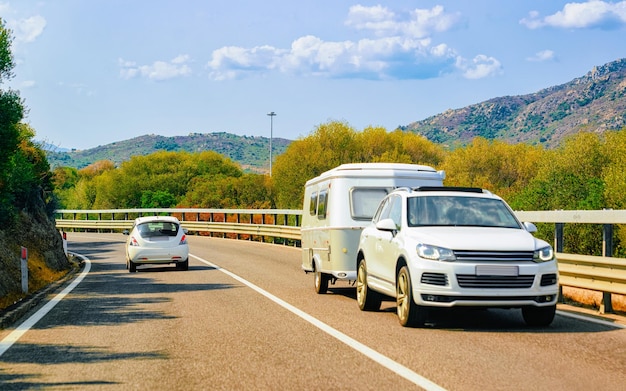 Camper en auto's op de weg aan de Costa Smeralda aan de Middellandse Zee in de zomer van het eiland Sardinië, Italië. Caravan camper op vakantie aan snelweg. Minivan rv op snelweg. Gemengde media.