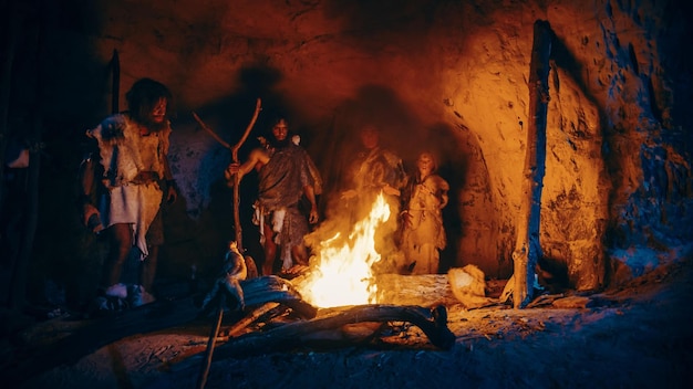 A campfire in a cave with a man standing around it.