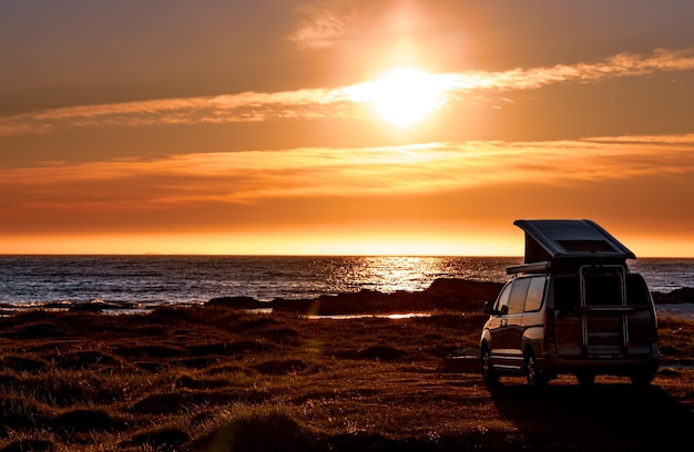 Camping auto minibus op het strand bij zonsondergang. prachtige natuur noorwegen natuurlijke landschap lofoten strand.