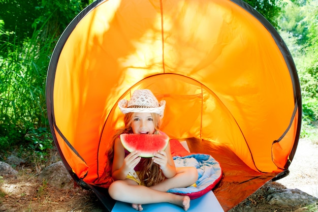 Camping children girl in tent eating watermelon slice