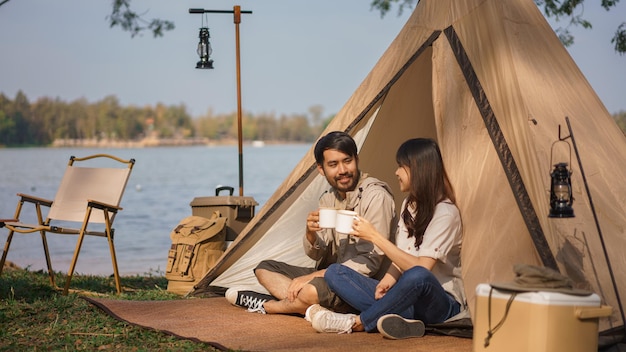 Camping concept Jonge paar backpackers zitten in de tent aan rammelende kopje koffie samen druppelen