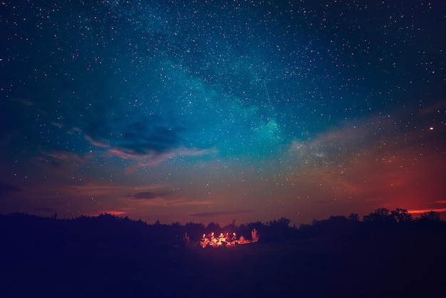 Foto fuoco da campeggio sotto l'incredibile cielo stellato blu con molte stelle e nuvole brillanti. concetto di attività ricreative all'aperto di viaggio.