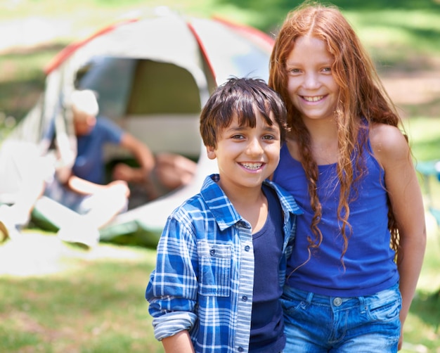 Camping kinderen en gelukkig in portret terwijl buiten banden en zorgeloos in het buiten avontuur Kinderen gezicht en glimlachen samen op vakantie vriendschap en vakantie in de natuur ontspannen en gras