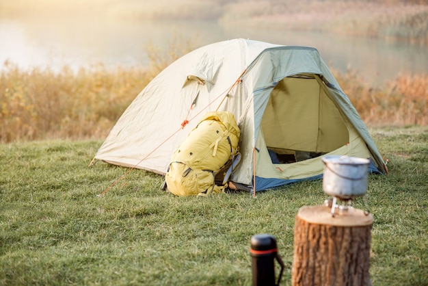 Photo camping place with tent, backpack and other equipment on the green lawn
