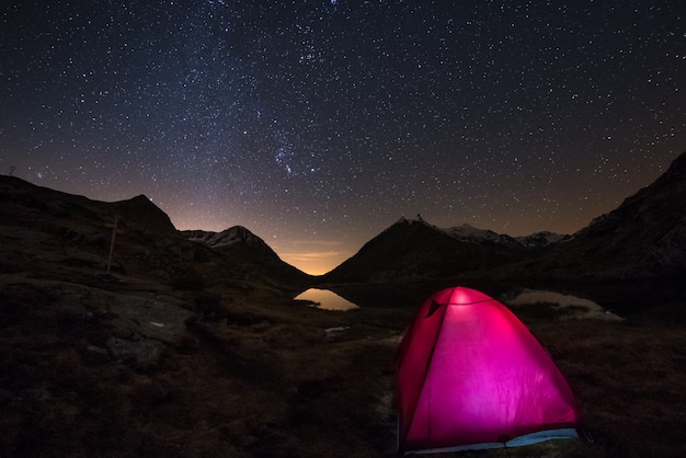 Camping under starry sky and Milky Way arc at high altitude on the italian french Alps