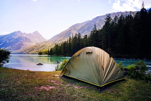 Camping tent in campground at national park Tourists camped in the woods on the shore of the lake on the hillside View of tent on meadow in forest Camping background