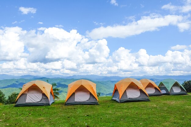 Foto tende da campeggio nella parte superiore della montagna con cielo blu e nuvole.