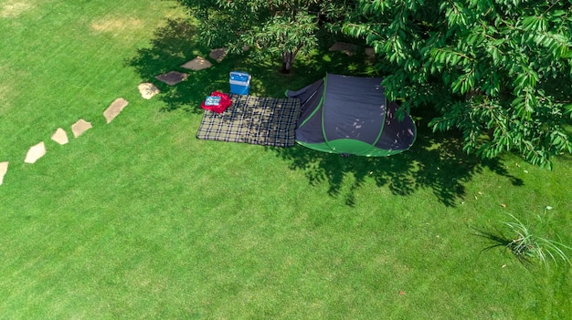 Campsite aerial view from above, tent and camping equipment under tree