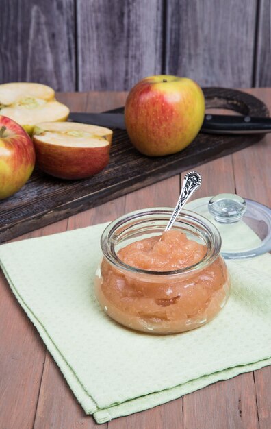 A can of Apple puree and sliced fresh apples on a wooden chopping Board on a wooden background