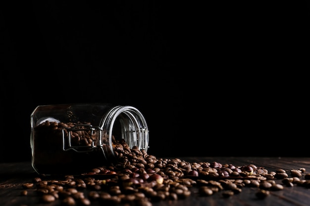 A can of coffee, scattered grains and black chocolate on a wooden table.