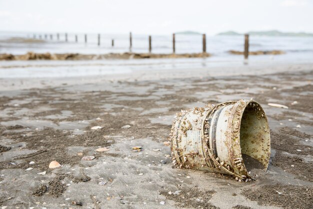 Foto un barattolo di vernice sulla spiaggia con sopra le vongole immondizia marina