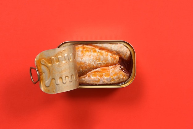 Can of pickled sardines on red