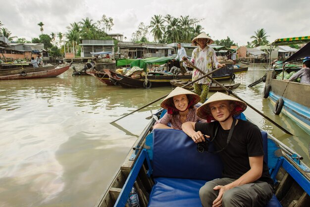 Can Tho, Vietnam - 02 april 2016: Een paar blanke toeristen reizen naar de drijvende markt Cai Rang in de buurt van Can Tho in Vietnam, Mekongdelta, waar mensen fruit en groenten van lokale productie kunnen kopen.