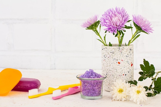 Can with sea salt toothbrushes soap and flowers of aster on a white background