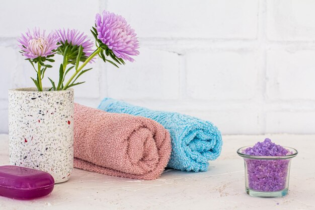 Can with sea salt towels soap and flowers of asters on a white background Woman wash accessories