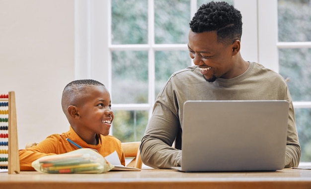 Can you help me Shot of a young father using a laptop while his son does homework at home