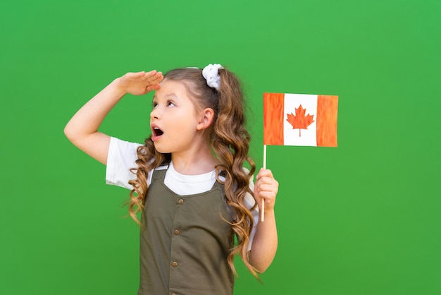 고립된 배경에 있는 어린 소녀의 손에 있는 캐나다 국기. 캐나다로 이주하여 교육을 받습니다.