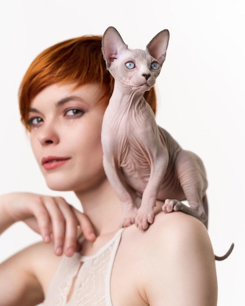 Canadian sphynx cat siede sulla spalla di una giovane donna rossa con i capelli corti messa a fuoco selettiva sul gatto