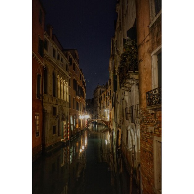 Foto canale in mezzo agli edifici contro un cielo limpido di notte